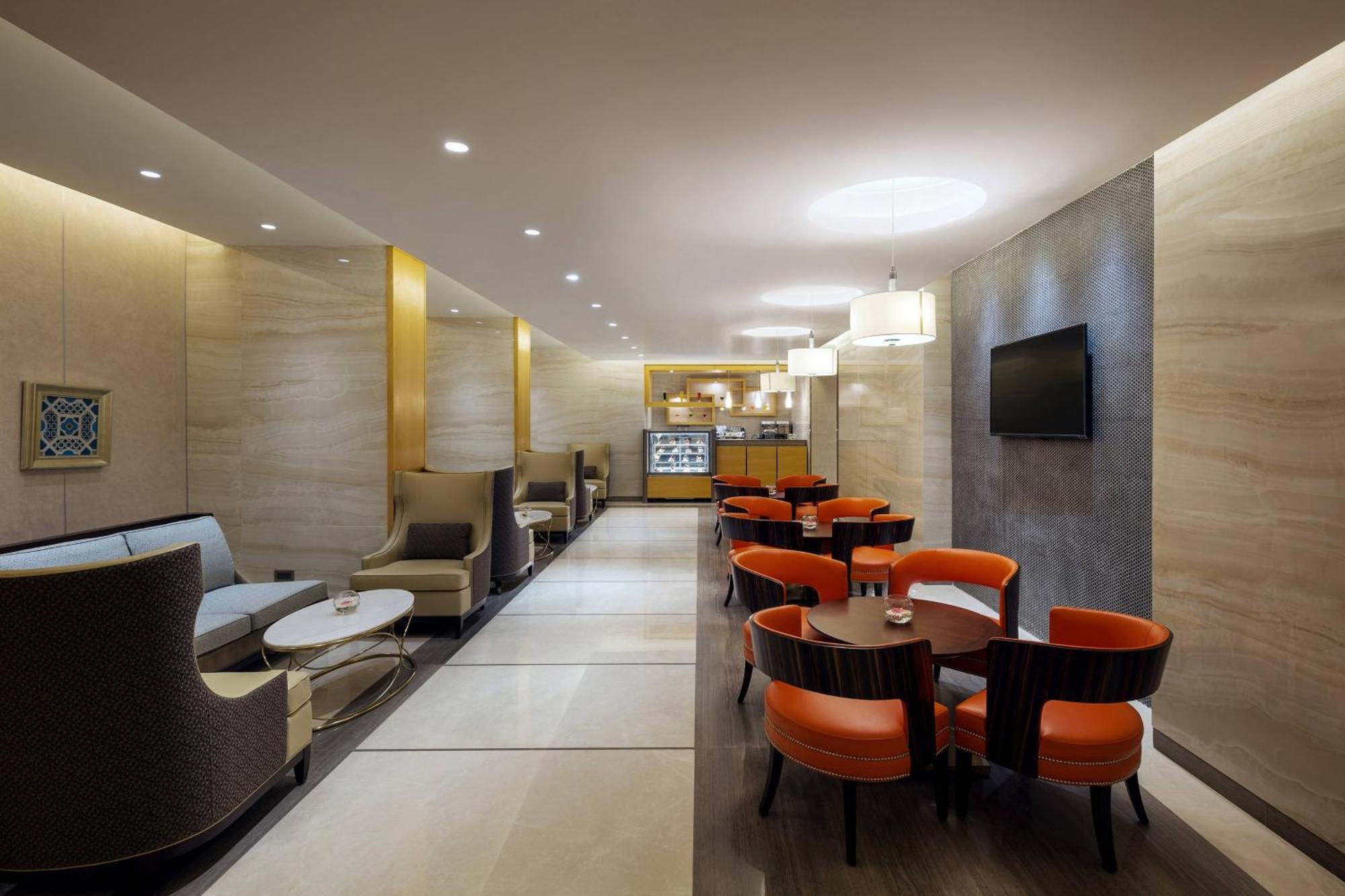 Sheraton Makkah Jabal Al Kaaba Hotel Mecca Екстер'єр фото The photo depicts a modern and elegant lounge or café area. The interior features soft, warm lighting and a combination of neutral and bold color schemes. On the left side, there are comfortable seating arrangements with light-colored sofas and chair